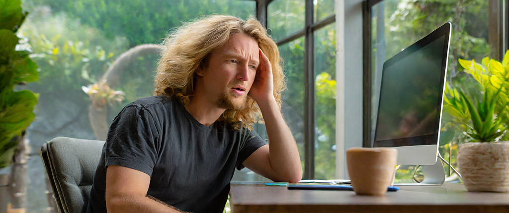 Frustrated man sits at computer